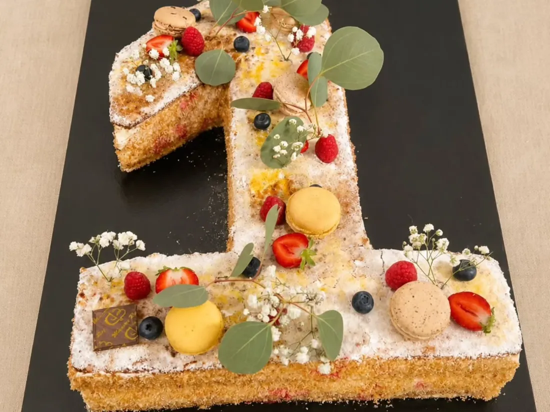 Gâteau en forme de chiffre 1 garni de fruits, macarons et fleurs