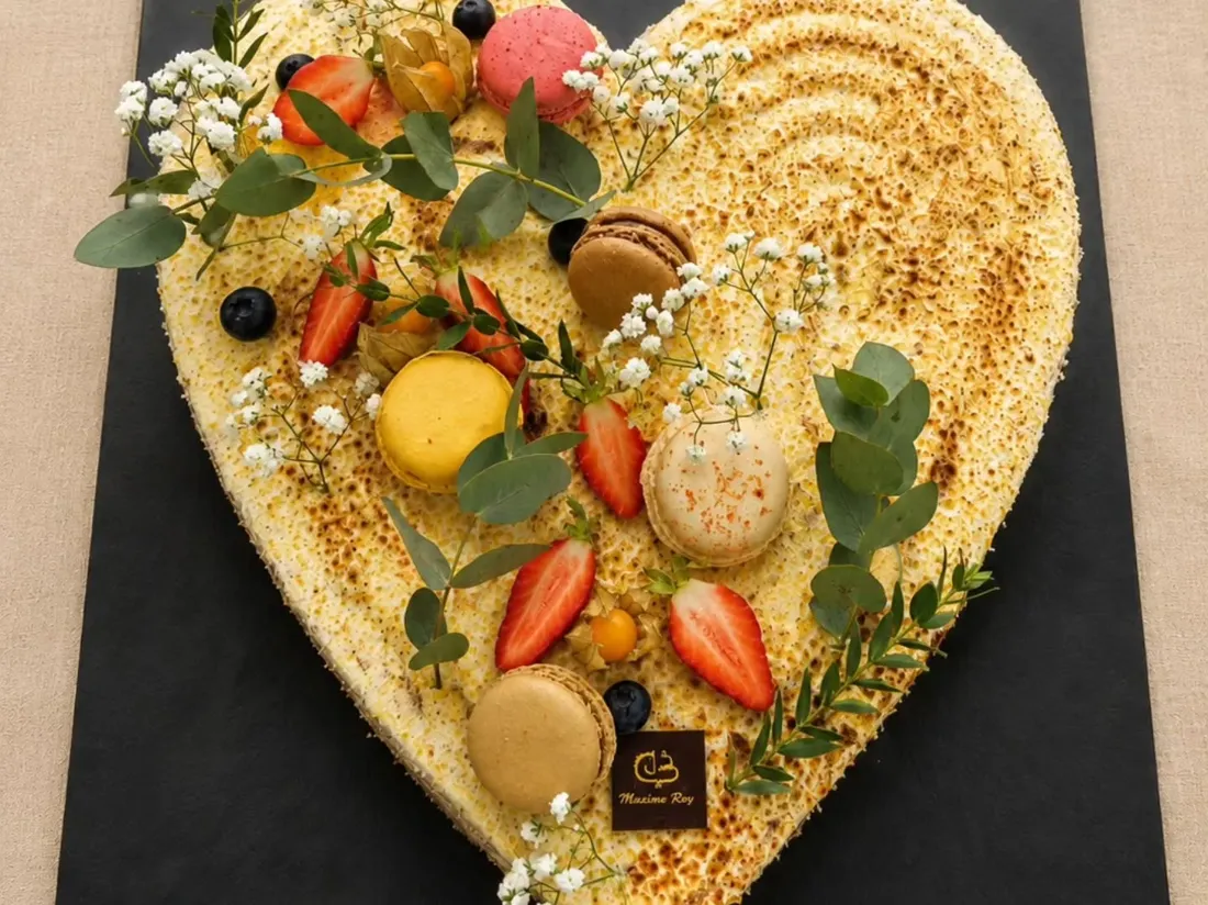 Gâteau d'événement en forme de cœur garni de fruits et macarons