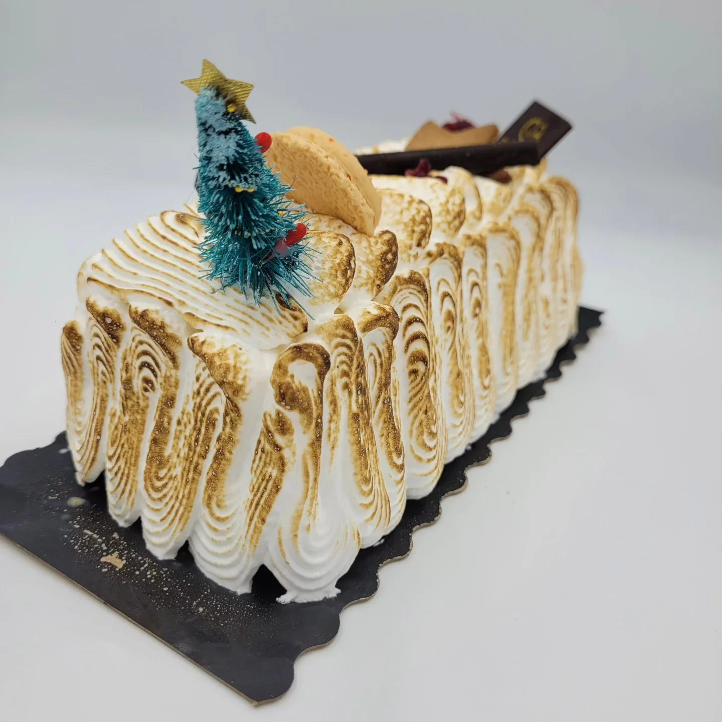 Bûche de Noël meringuée et dorée, décorée d'un petit sapin